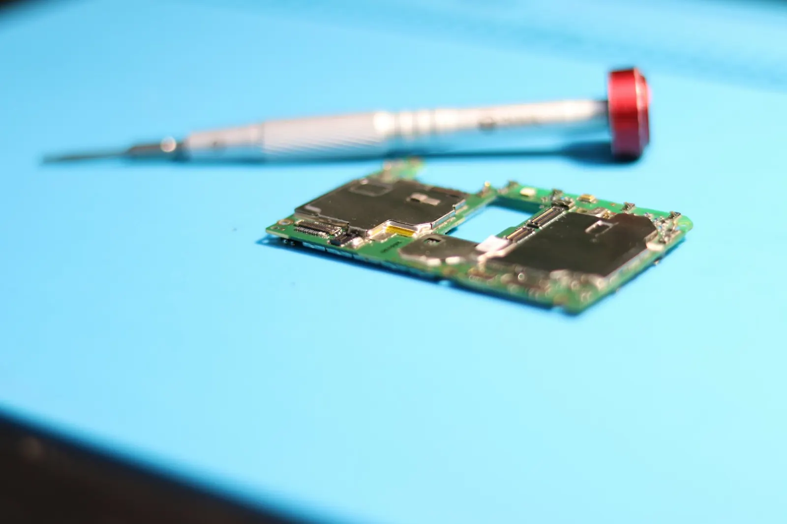 Tarjeta electrónica y destornillador sobre una mesa de trabajo